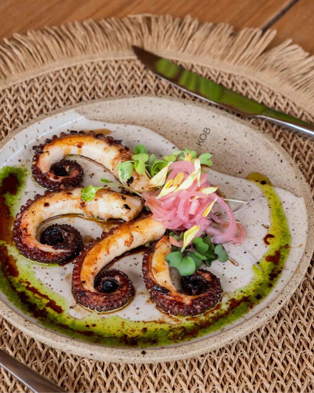 Plated dish of octopus with garnishes on a textured plate